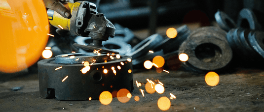 Angle grinder in use with sparks on a workshop background for stainless steel polishing