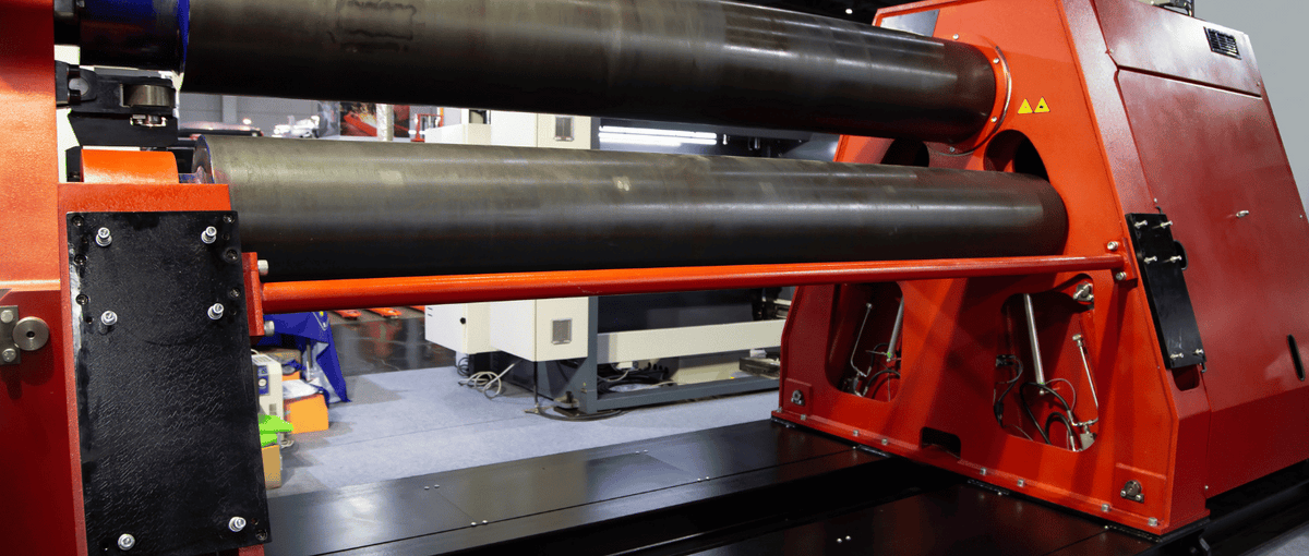 Industrial heavy-duty plate rolling machine used for bending large stainless steel sheets in precision fabrication.