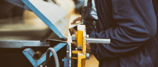 Operator using an industrial sheet metal bending machine for precision forming during fabrication.