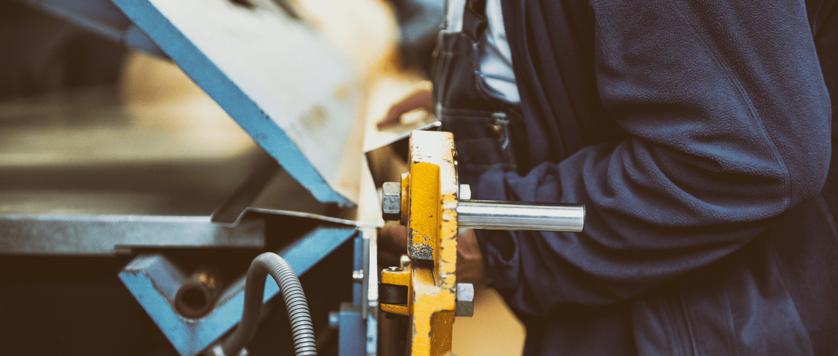 Operator using an industrial sheet metal bending machine for precision forming during fabrication.