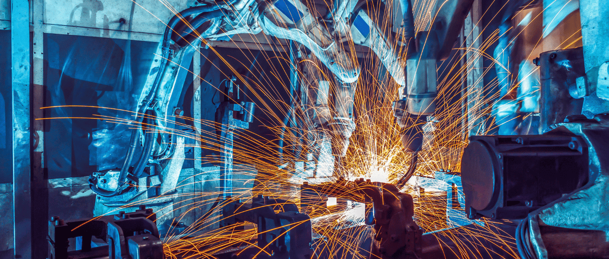 Robotic CNC welding machine in a factory setting with sparks flying, indicating automation and technology.