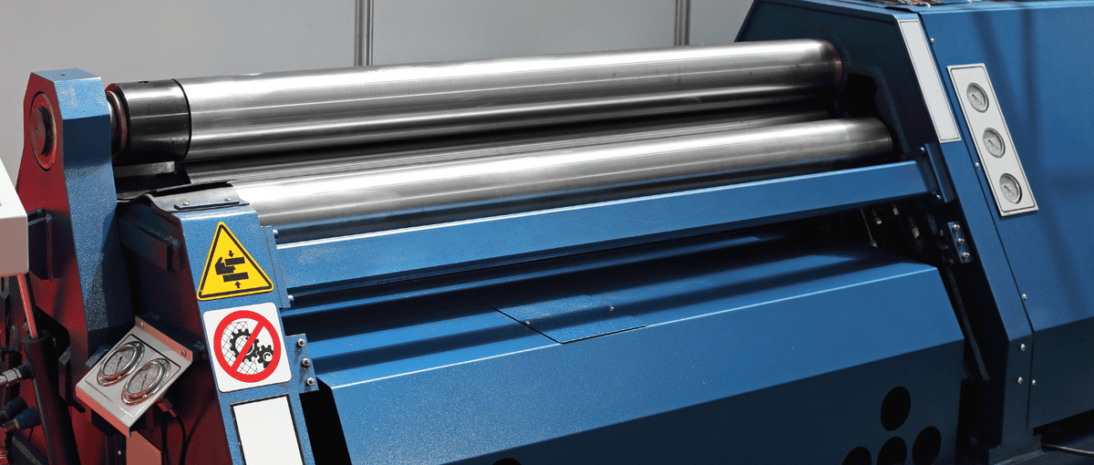 Blue Stainless Steel metal rolling machine with safety signs on a tiled wall background