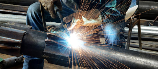 Worker welding a stainless steel tube during fabrication, showcasing precision by South African steel suppliers.