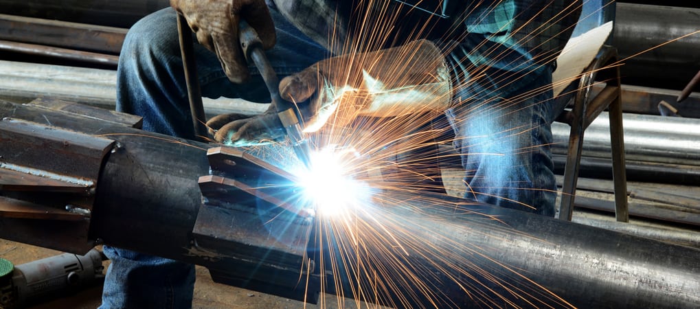 Worker welding a stainless steel tube during fabrication, showcasing precision by South African steel suppliers.